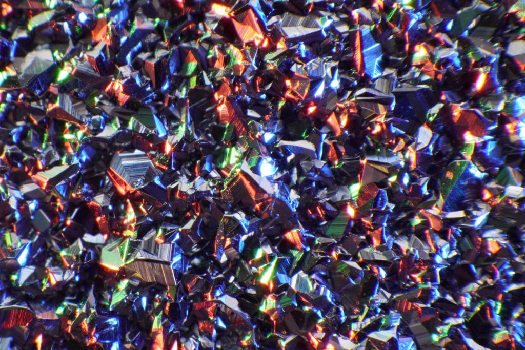 Osmium besitzt eine Kristallstruktur, welche die Umgebung reflektiert und das Edelmetall unter dem Mikroskop glitzern lässt